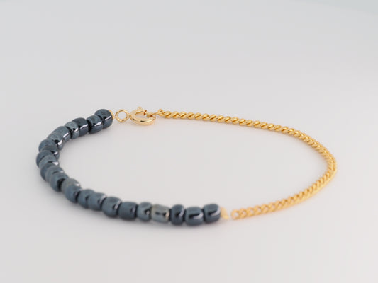 Bracelet with blue beads and gold chain on a light gray background