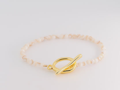 Gold bracelet with a leaf-shaped clasp on a light gray background