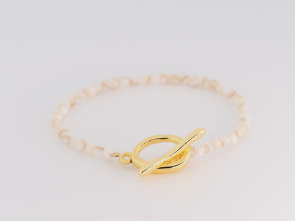 Gold bracelet with a unique clasp on a light gray background