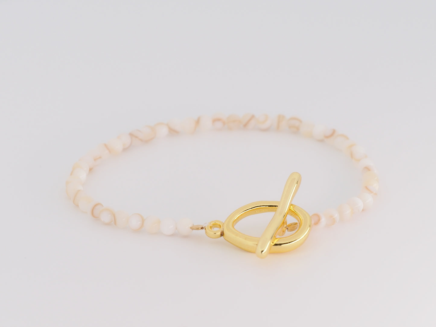 Gold bracelet with a toggle clasp on a light background