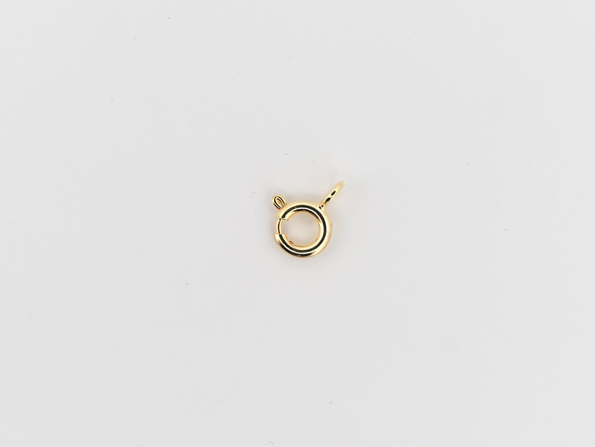 Gold necklace clasp on a light gray background