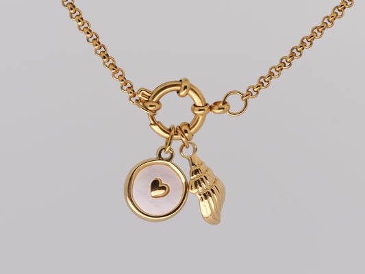 Gold necklace with heart and shell charms on a light gray background