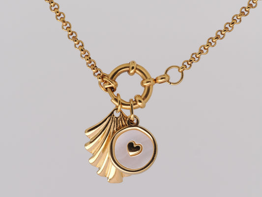 Gold necklace with a scallop shell and heart pendant on a gray background