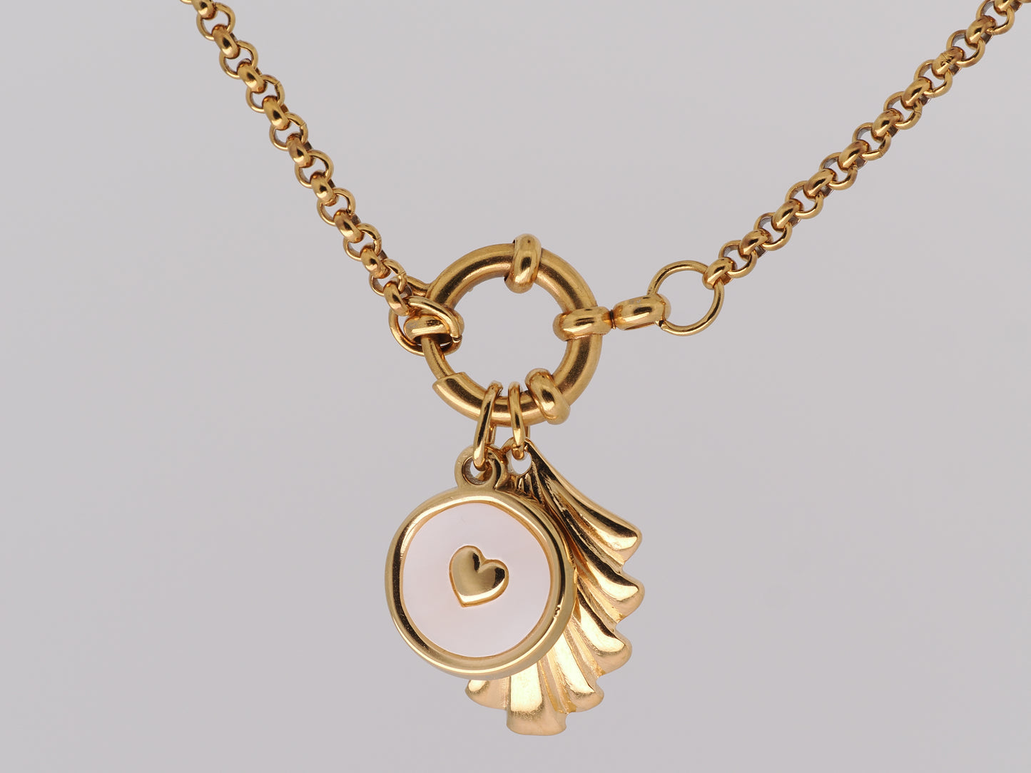 Gold necklace with a heart-shaped pendant on a gray background