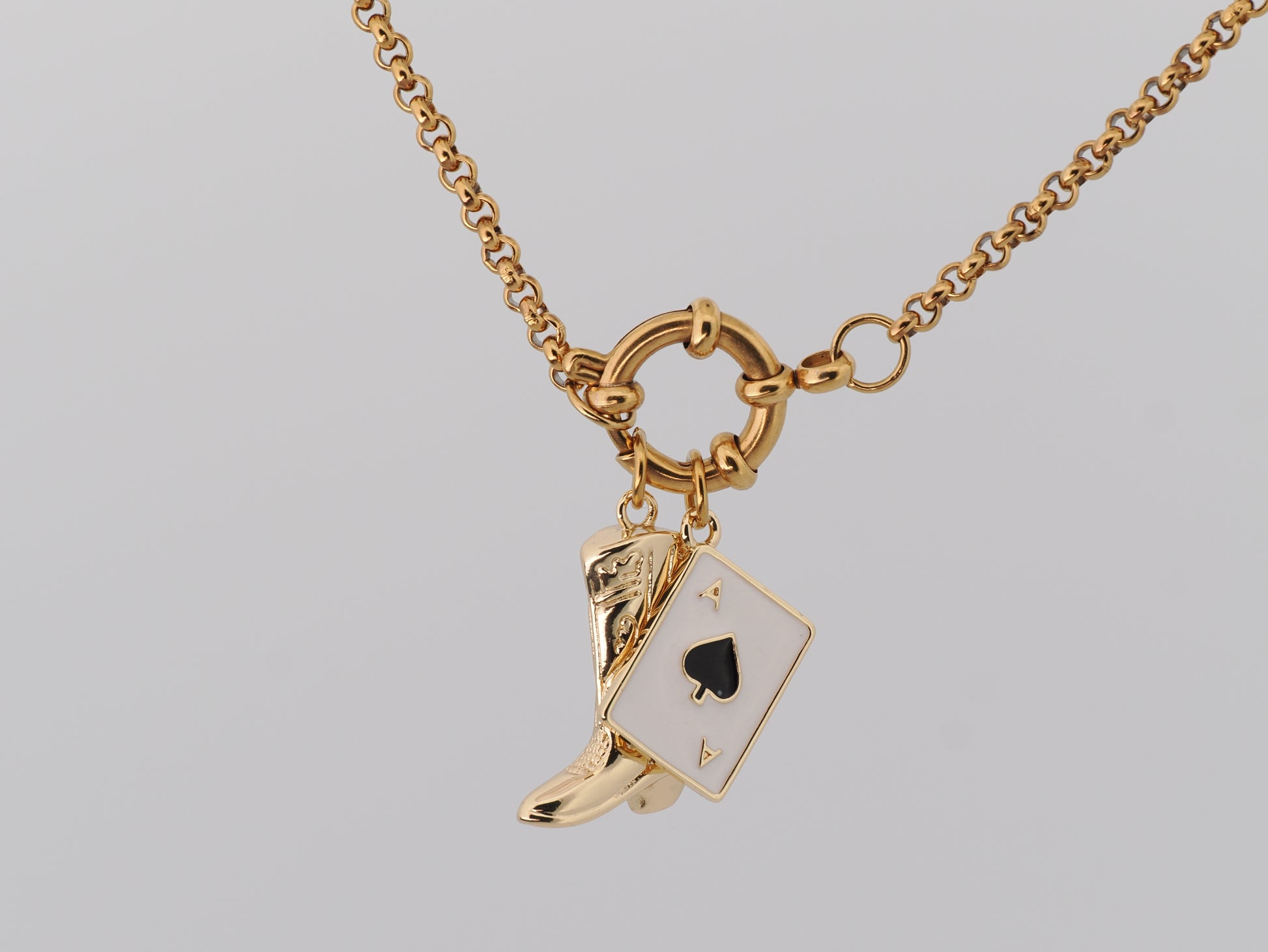 Gold necklace with a boot and card charm on a gray background