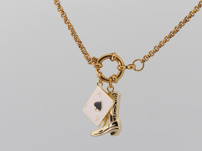 Gold necklace with a spade card and cowboy boot charm on a gray background