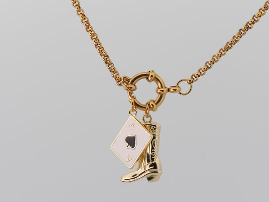 Gold necklace with a spade card and cowboy boot charm on a gray background