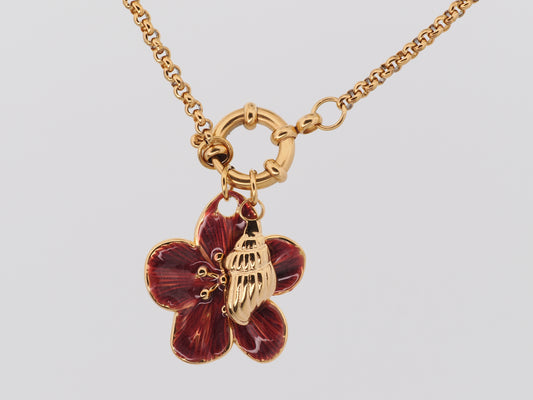 Gold necklace with a red flower pendant on a light gray background