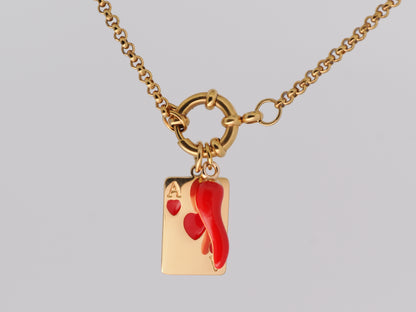 Gold necklace with a red heart and card charm on a gray background