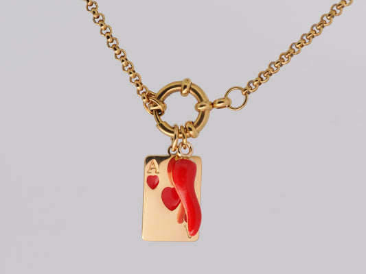 Gold necklace with a red heart and card charm on a gray background