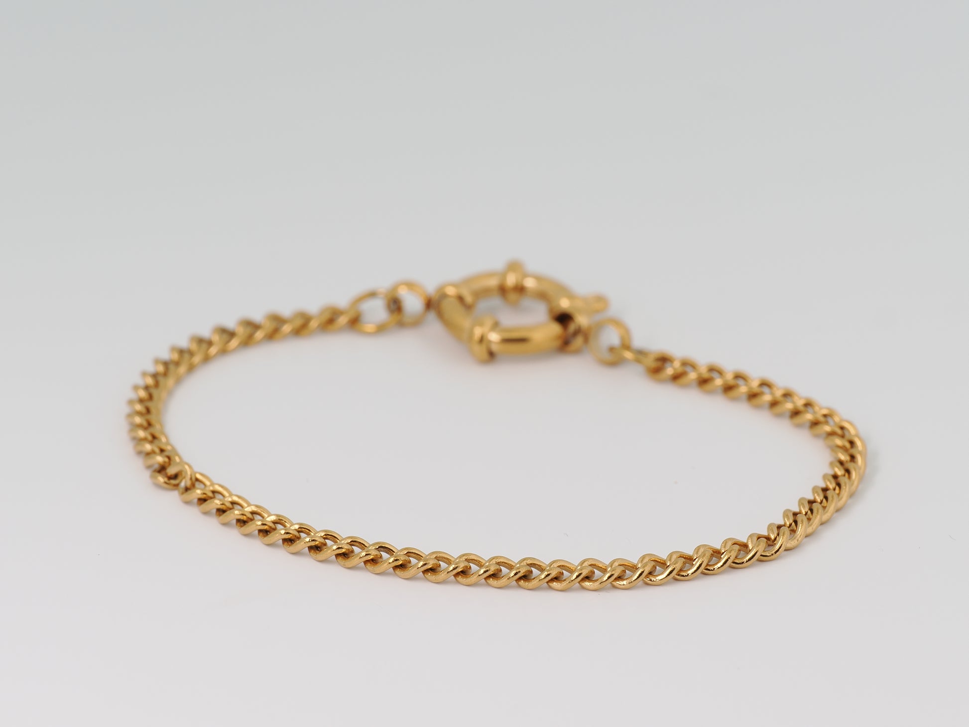 Gold chain bracelet on a light gray background