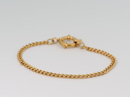 Gold chain bracelet on a light gray background