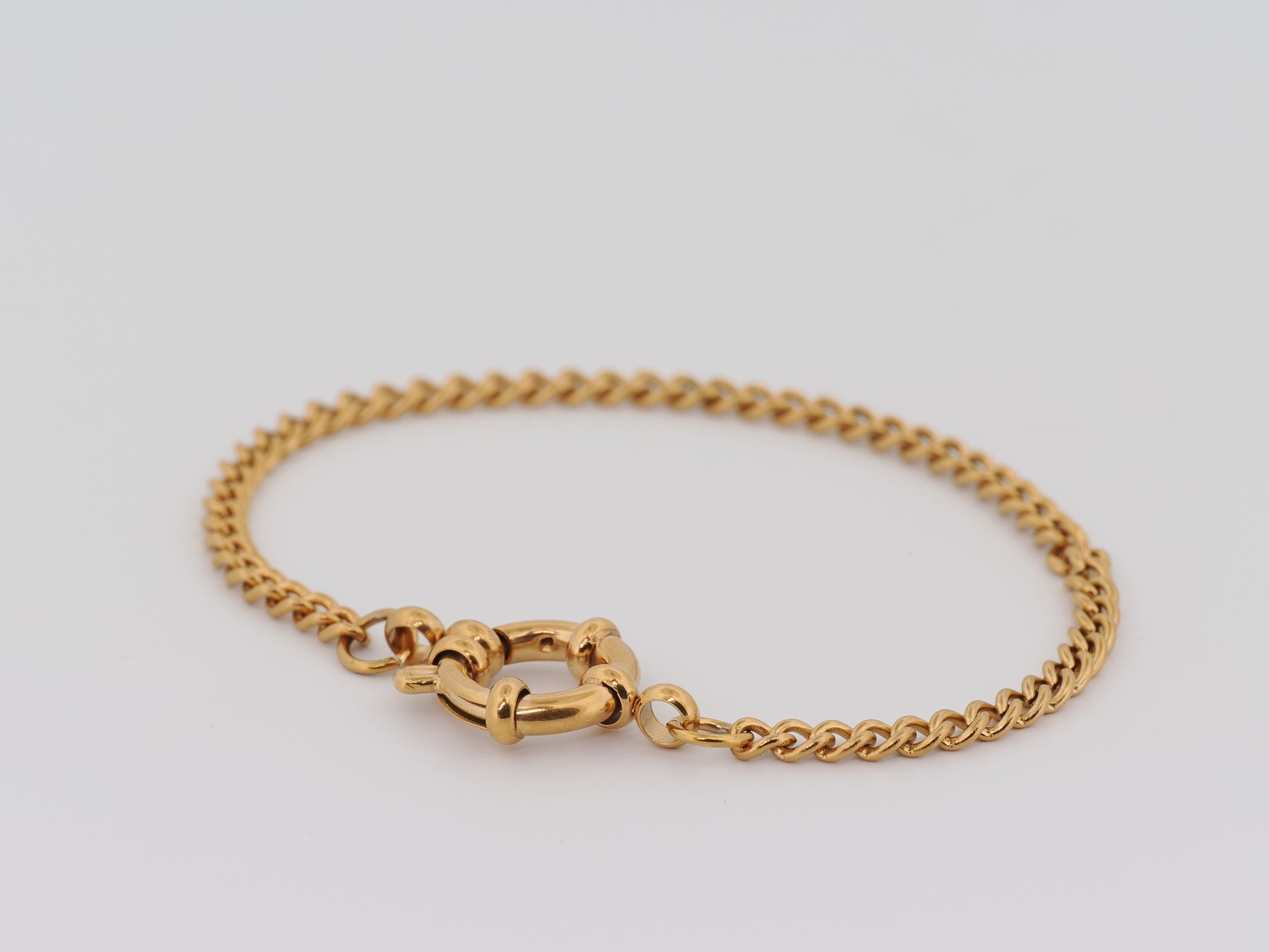 Gold chain bracelet on a light gray background