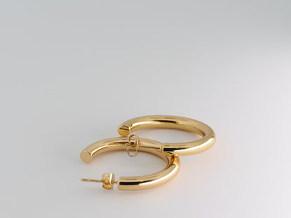 Gold hoop earrings on a light gray background