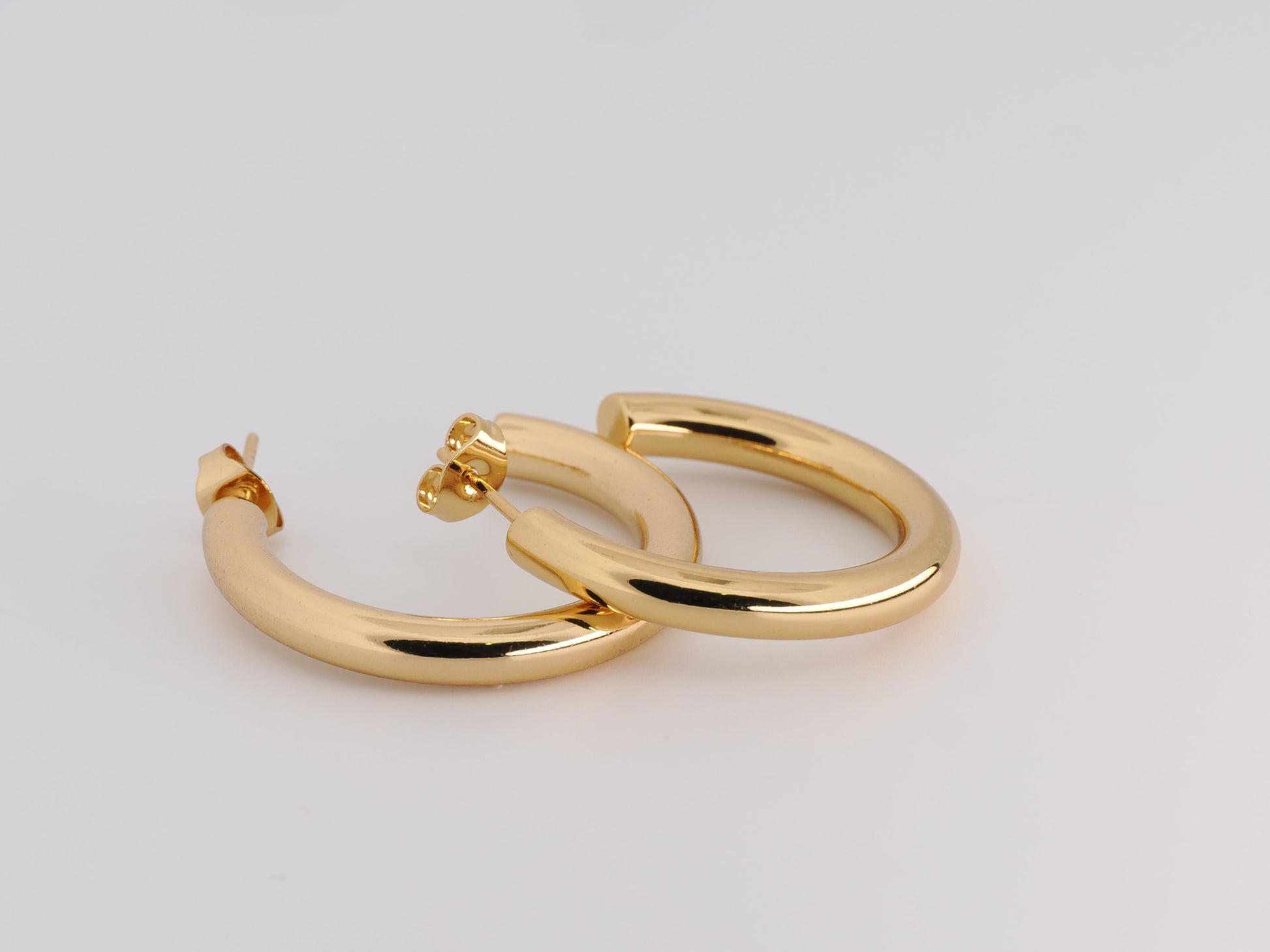 Gold hoop earrings on a light gray background