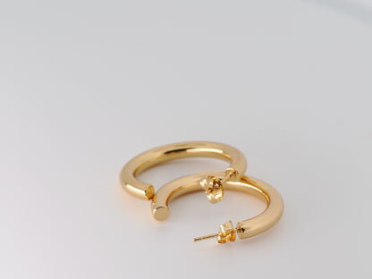 Gold hoop earring on a light gray background