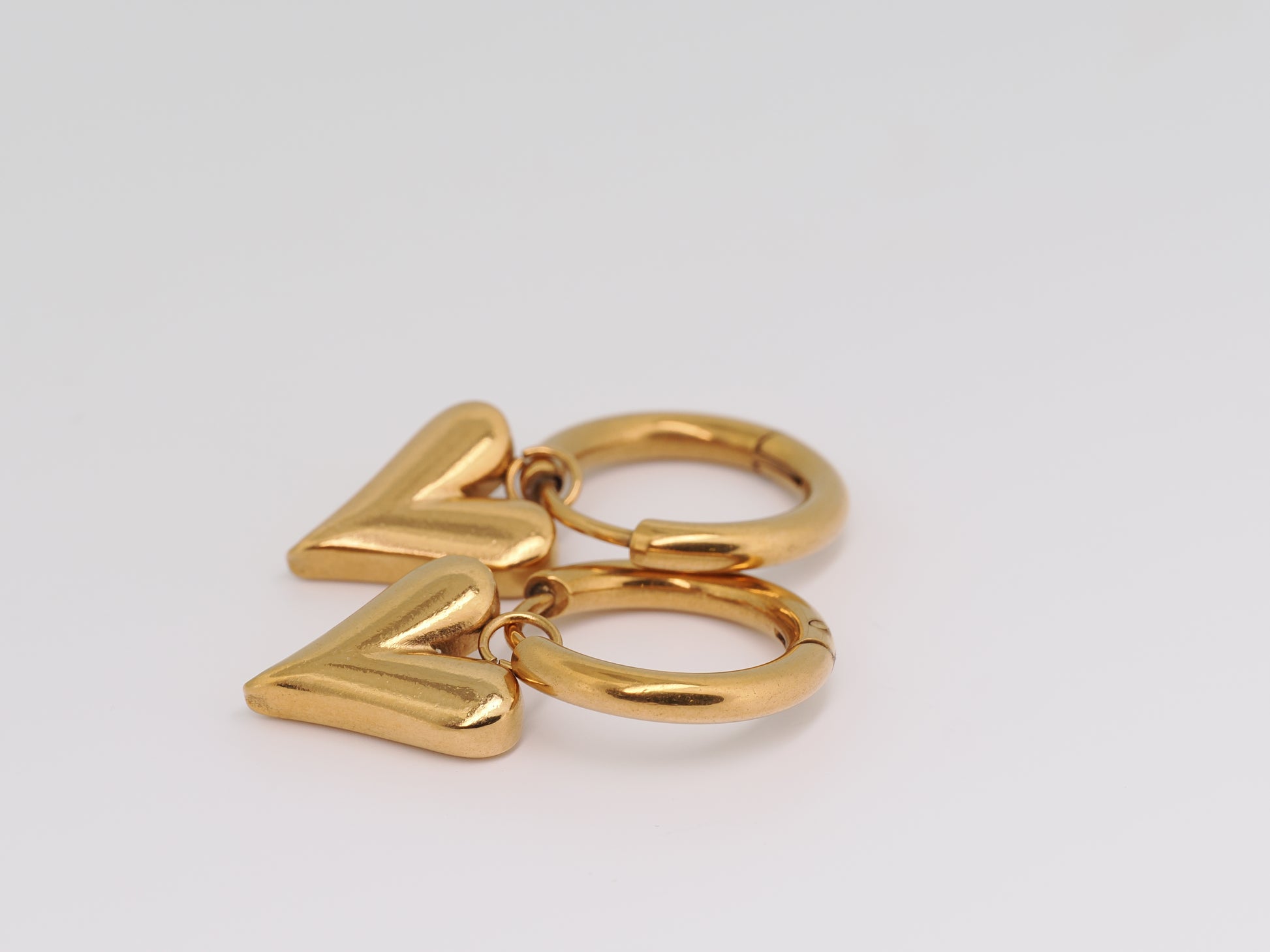 Gold hoop earrings with 'V' charms on a light gray background