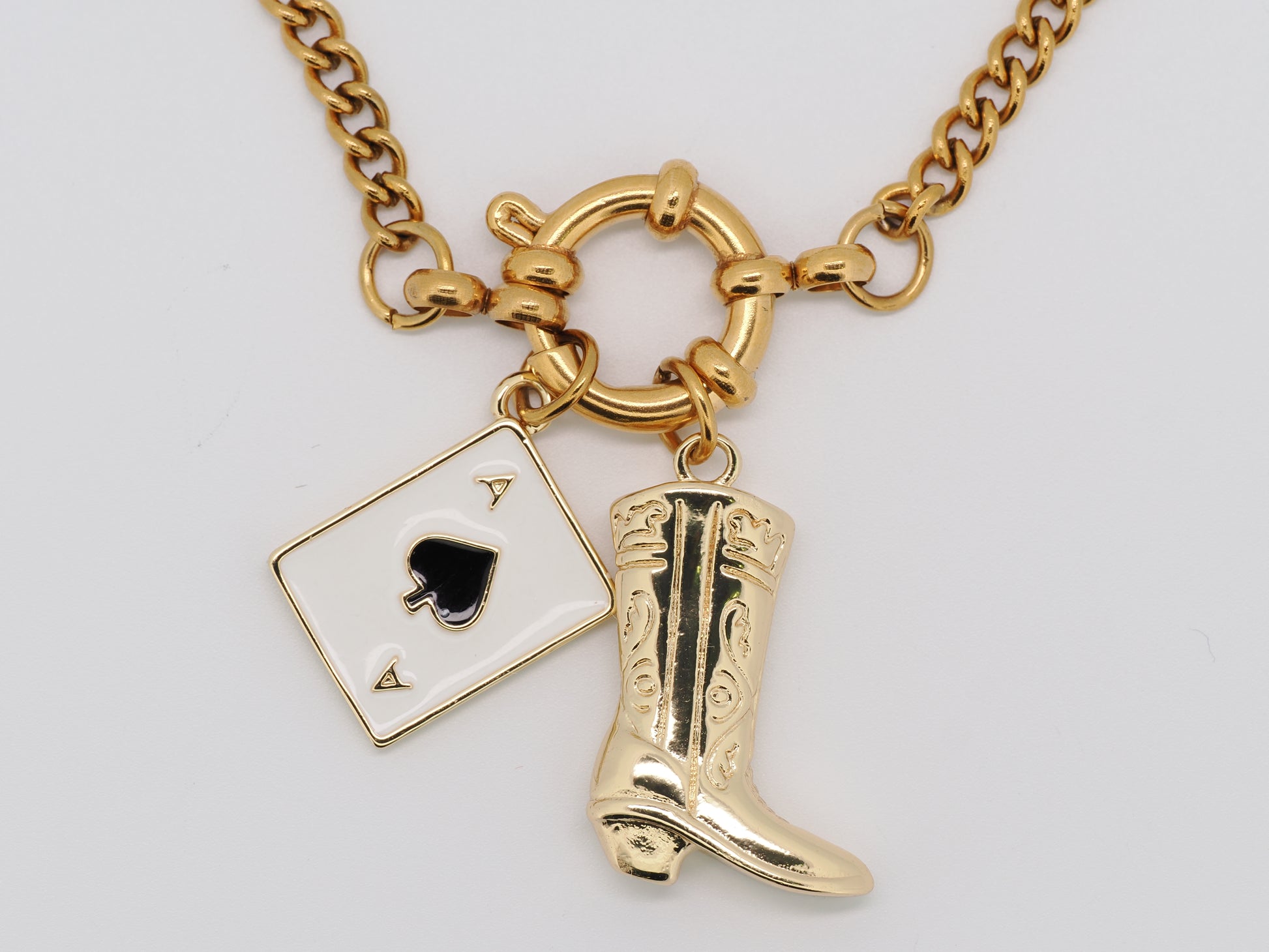 Gold necklace with a spade card and cowboy boot charm on a white background