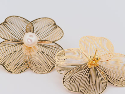 Gold flower-shaped earrings with a pearl center on a light gray background