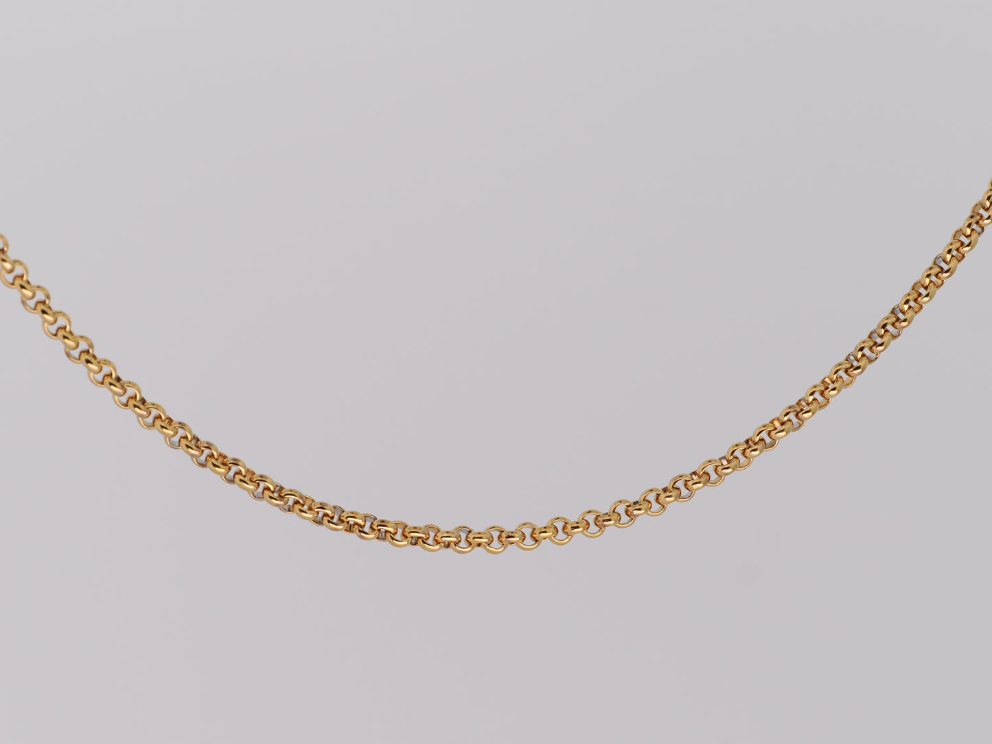 Gold chain necklace on a light gray background