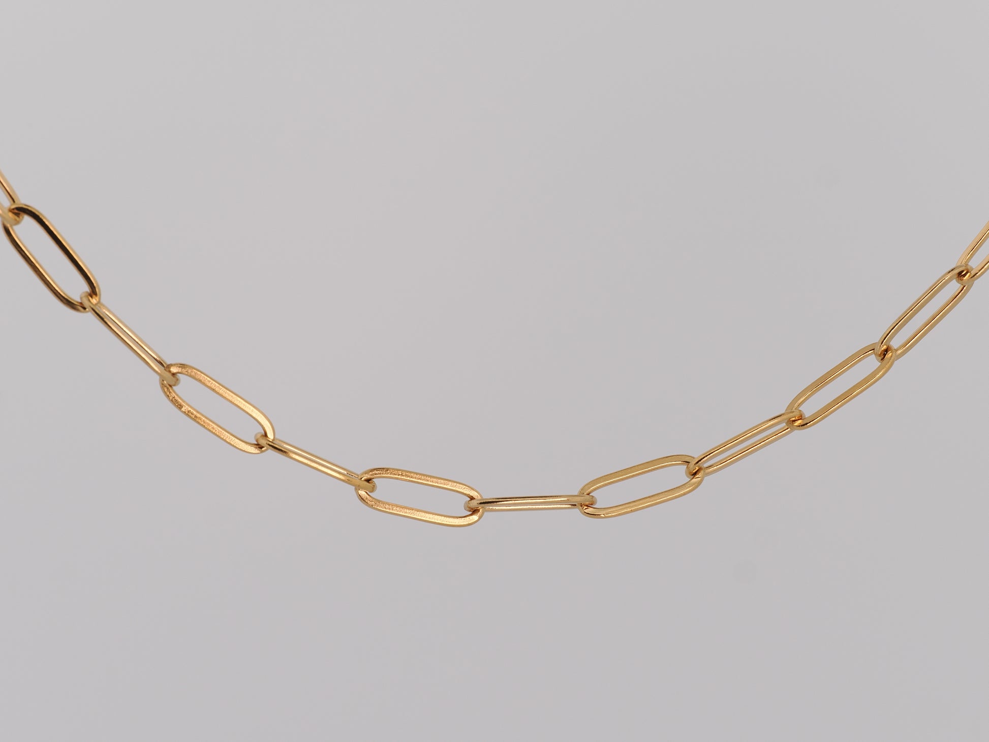 Gold chain necklace on a gray background