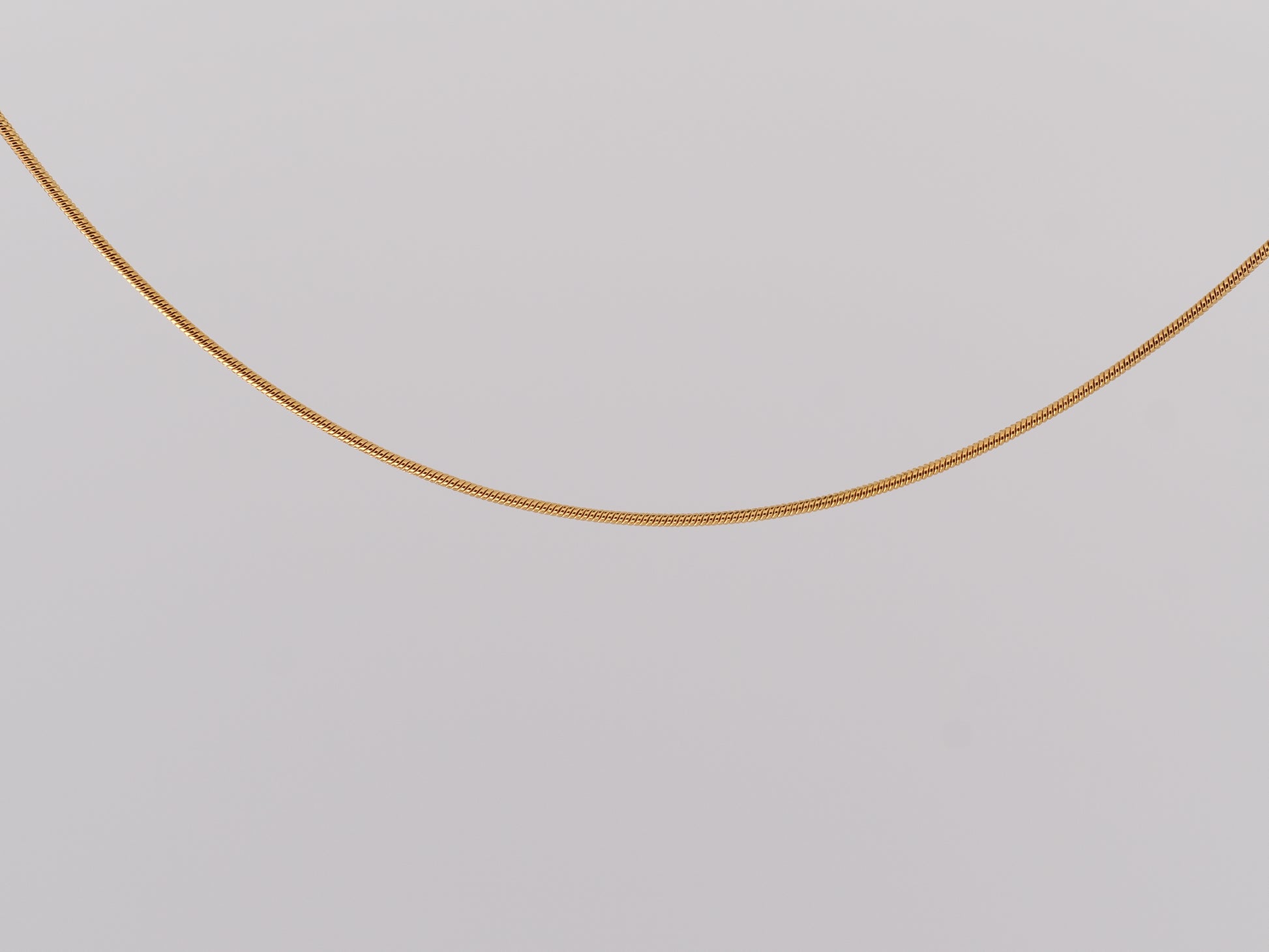 Gold chain on a light gray background
