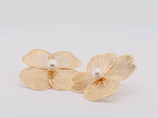 Gold flower-shaped earrings with pearls on a light gray background