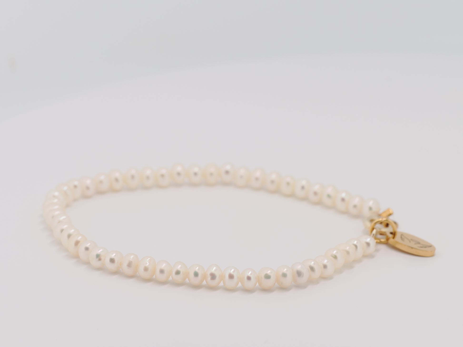 Pearl bracelet with a gold clasp on a light gray background