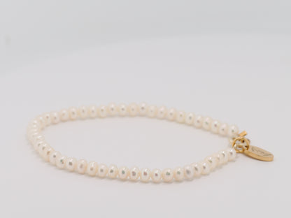 Pearl bracelet with a gold clasp on a light gray background