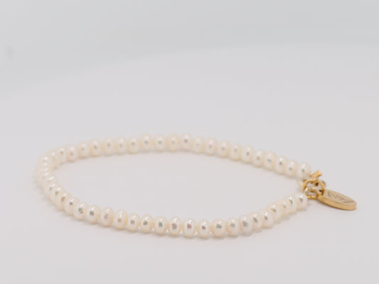 Pearl bracelet with a gold clasp on a light gray background