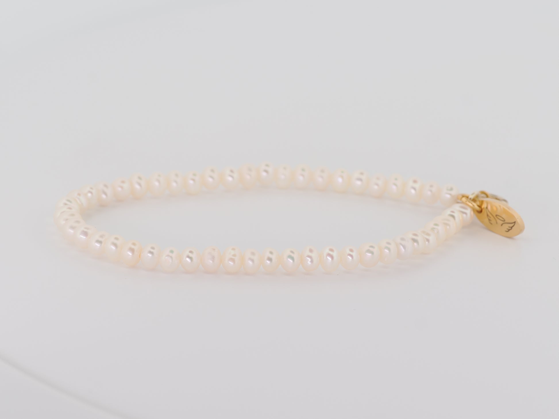 Pearl bracelet with a gold clasp on a light gray background