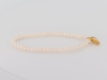Pearl bracelet with a gold clasp on a light gray background