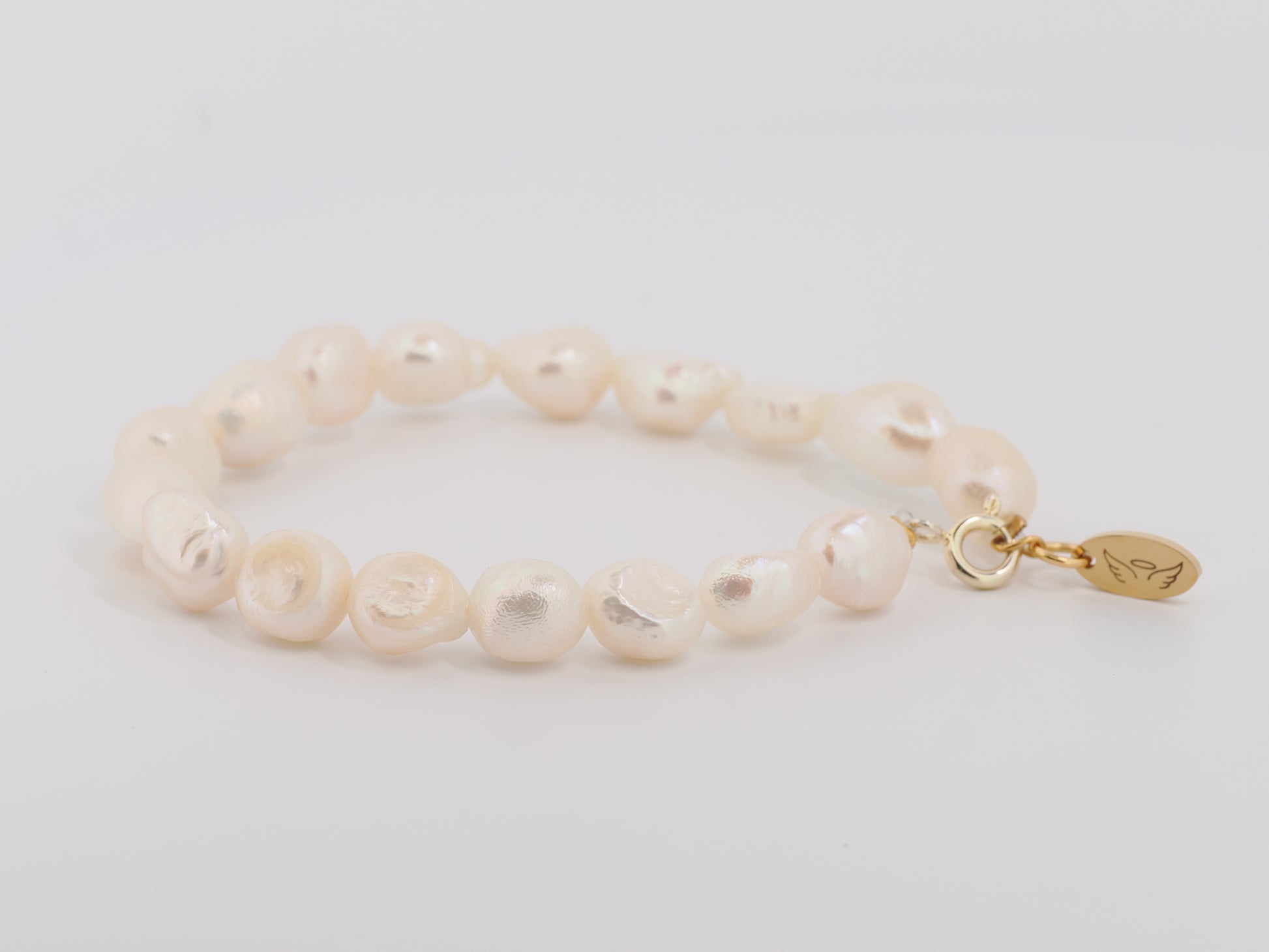 Pearl bracelet with a gold clasp on a light gray background