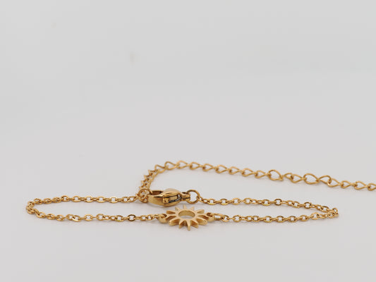 Gold chain bracelet with a sunflower clasp on a light gray background