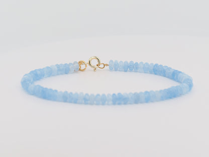Light blue beaded bracelet with a gold clasp on a light gray background