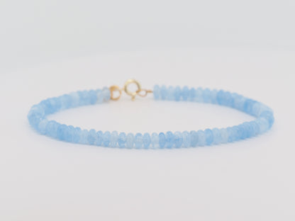 Light blue beaded bracelet with a gold clasp on a light gray background