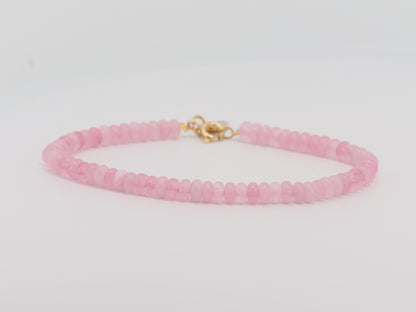 Pink beaded bracelet with a gold clasp on a light gray background