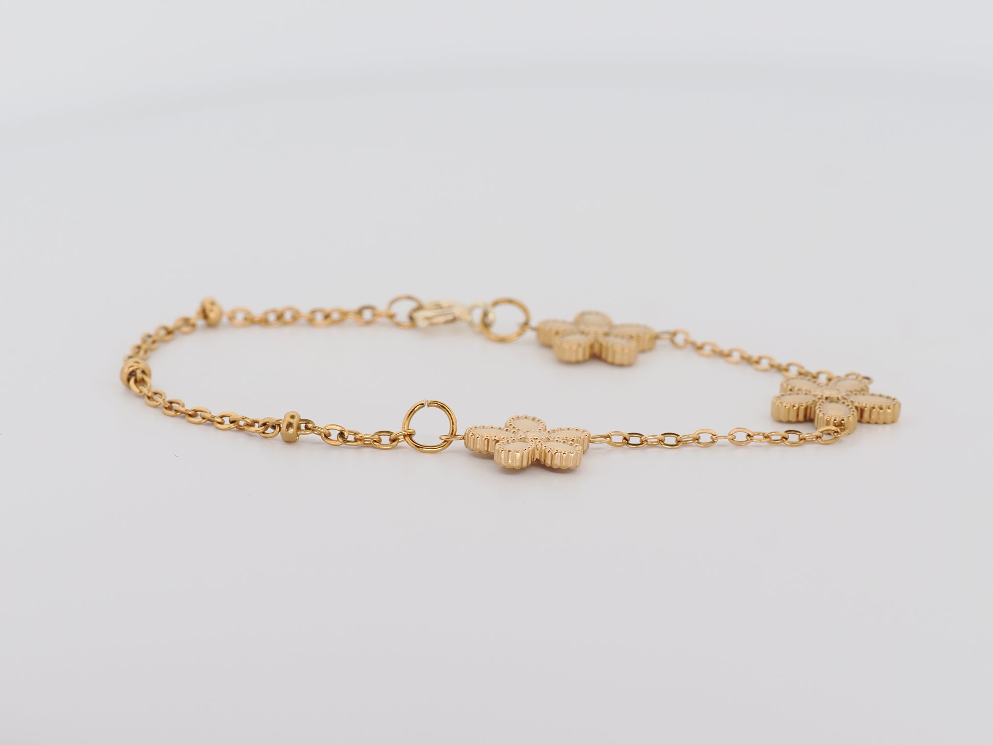 Gold bracelet with floral links on a light gray background