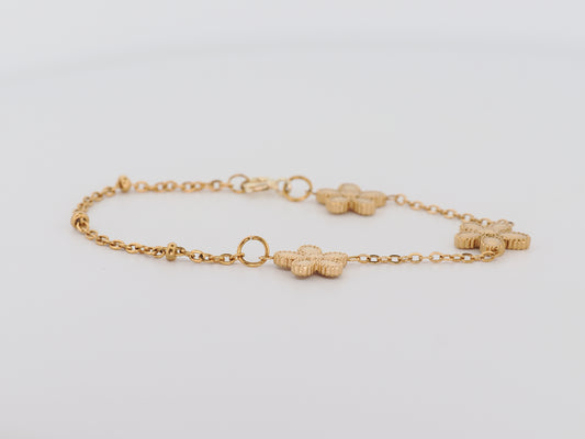 Gold bracelet with floral links on a light gray background